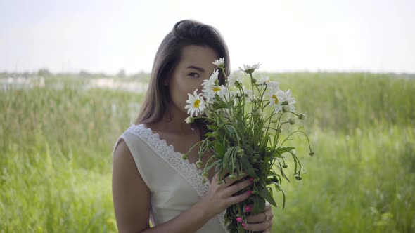 Portrait Glamorous Young Girl with Brunette Hair Wearing a Long White Summer Fashion Dress Standing alt