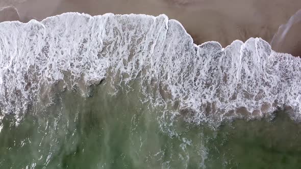Beautiful aerial view of the drone, the ocean washes the golden shore with these waves.