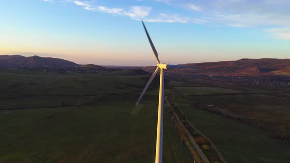 White lone windmill rotates at sunset in the mountains