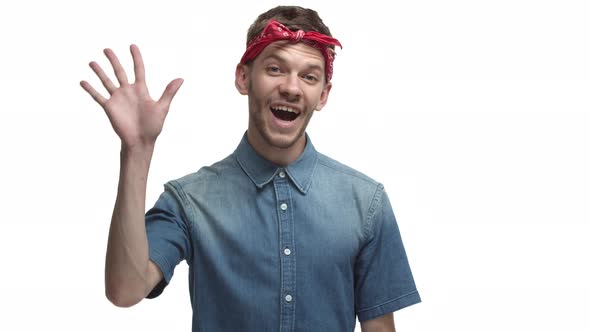 Friendly Bearded Guy with Red Bandana Waving Hand and Smiling Saying Hello Greeting you Standing