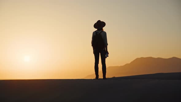 Young photographer with a camera looking at the mountains alt