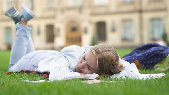 Upset and Tire Student Girl Lying on The Lawn Near the College