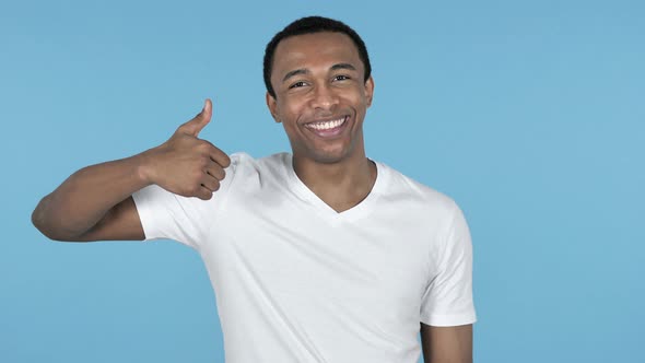 African Man Gesturing Thumbs Up Blue Background alt