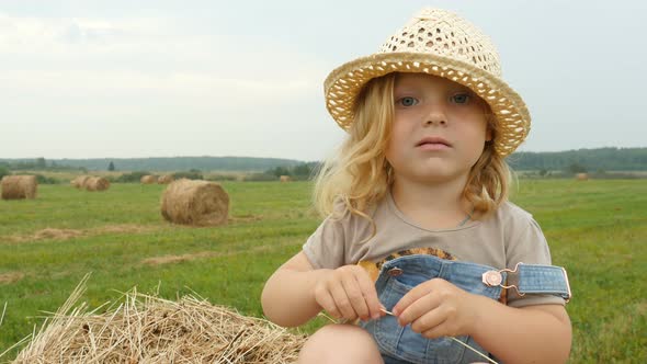 Funny Child Sitting on Haystack on Farmer Field. Farmer Daughter Walking in Field