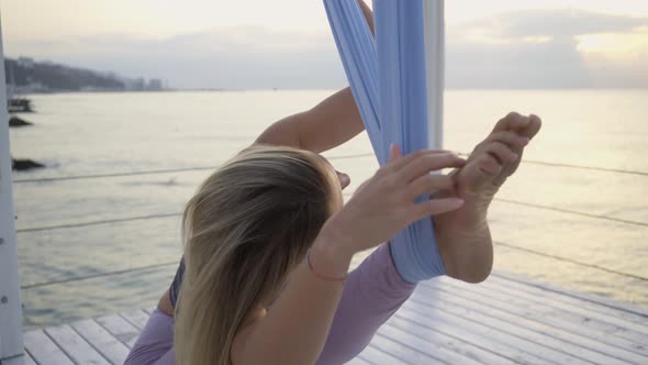 Woman in Sportswear Does Stretching Exercises with Sling