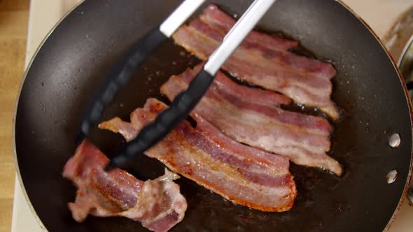 Cooking Bacon Being Flipped in a Pan alt
