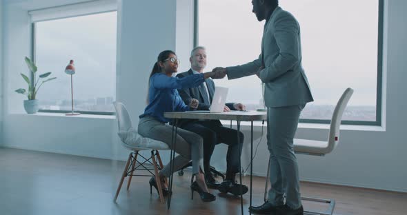 Couple of multi-ethnic business people doing handshake on job interview alt