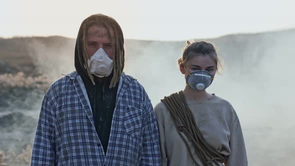 Portrait of exhausted girl and boy in gas mask from the group of survivor people. alt