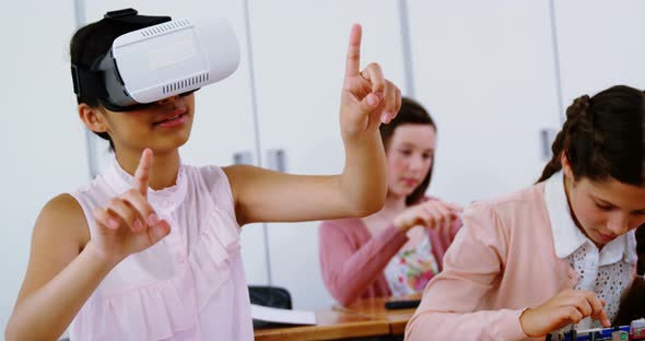 Schoolgirl using virtual reality headset in classroom alt