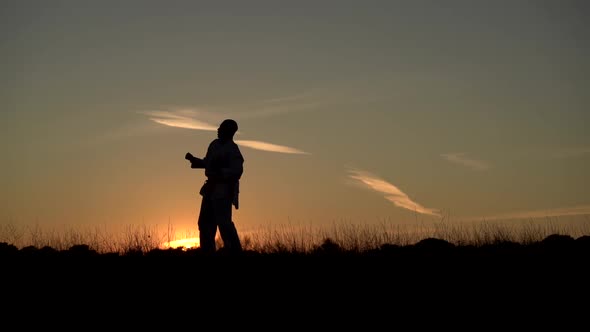 Young man practicing martial arts in nature at sunset alt