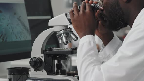 African American Engineer Working with Microscope in Lab alt