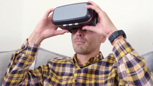 Young man using virtual reality headset in living room at home 4k