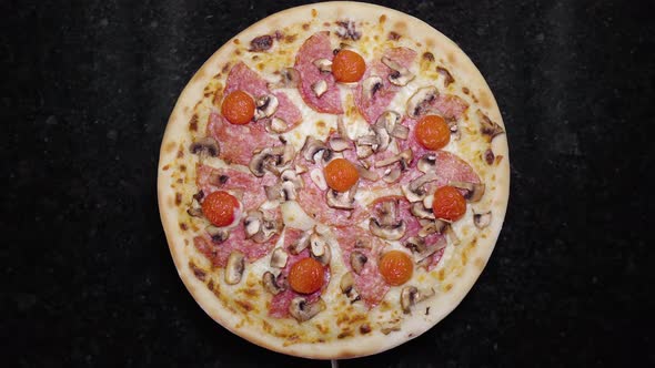 Top View of Whole Fresh Round Pizza with Tomatoes and Mozzarella Cheese Turns on a Table