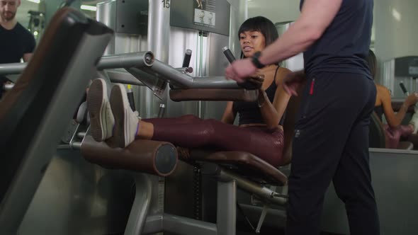 Woman with Instructor Doing Leg Extension Workout alt