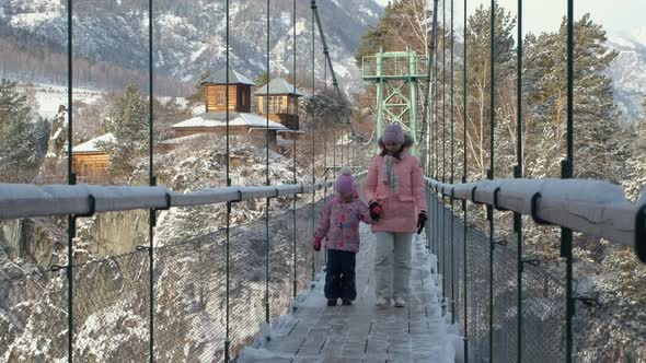 Female with Daughter Walking on Suspension Bridge alt