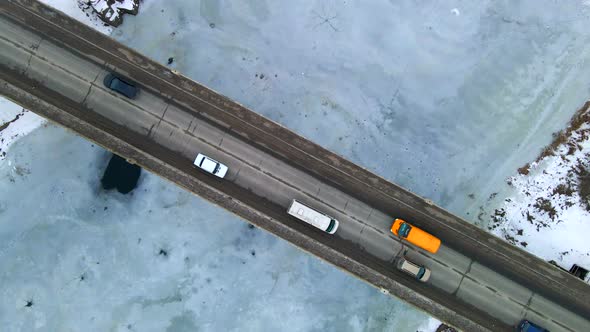 Topdown View of Cars Passing Small Bridge Over Frozen Small River in European City alt