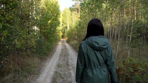 Girl Walking in the Forest Along the Road in Autumn
