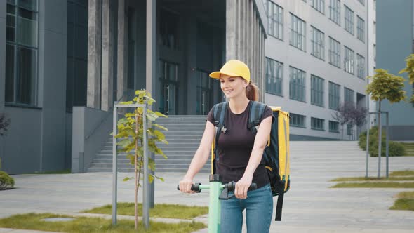 Smiling Young Delivery Woman Riding Scooter and Hurrying to Deliver Hot Food to alt