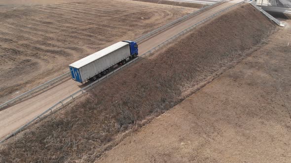 Aerial View of a Large Truck with a Trailer Driving Along a Dirt Road in Search of a Place for a U alt