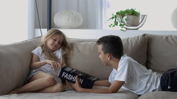 Lovely Children Brother and Sister Reading a Book on the Sofa