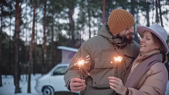 Happy Couple Light Sparklers and Kiss in the Woods in Winter Enjoying Van Life
