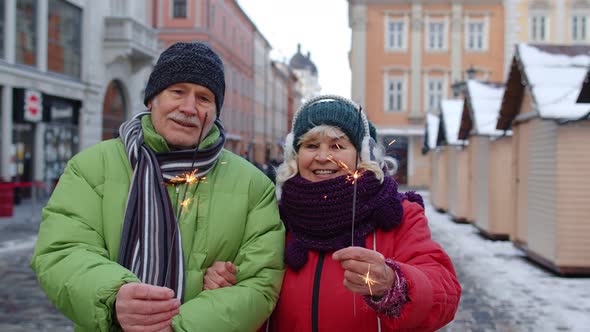 Senior Couple with Burning Sparklers Bengal Lights Celebrating Anniversary Making a Kiss on Street alt
