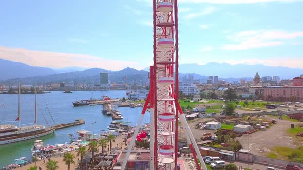 Aerial photography of a drone flying around a Ferris wheel on the seashore alt
