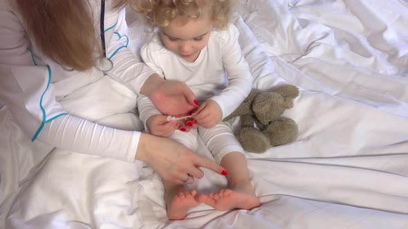 Female Doctor Hands Stick Strapping Adhesive on Cute Little Girl Leg in Bed
