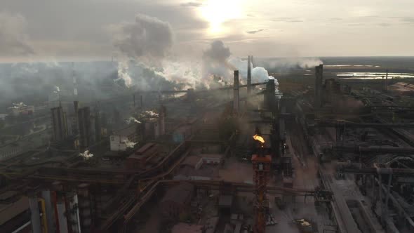 Steel Factory Pipes During Sunrise Time. High Above Metallurgical Plant and Smoke Cloud Is Coming