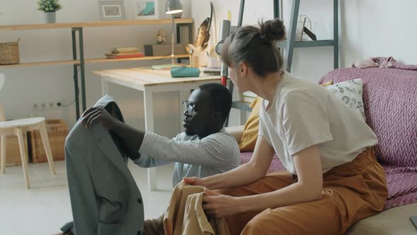 Young Multiethnic Couple Checking Clothes and Speaking at Home alt