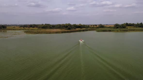 Aerial Shot Following Speed Boat in the Dark Green Lake Entering River Ukraine