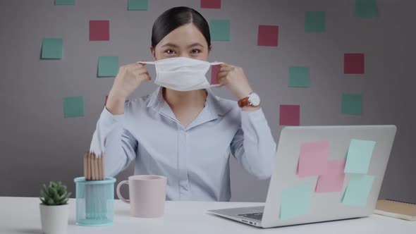 Asian woman wearing protective face mask working on a laptop