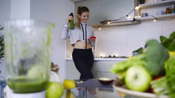 Woman with Phone Make Fresh Cocktail on Kitchen