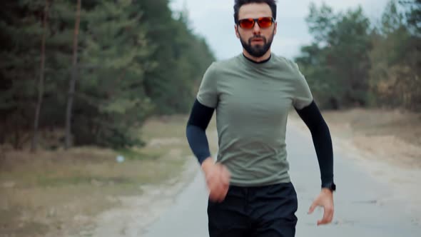 Running Man In Forest At Sunset. Runner Man Fit Athlete Legs Jogging On Trail Ready To Triathlon. alt