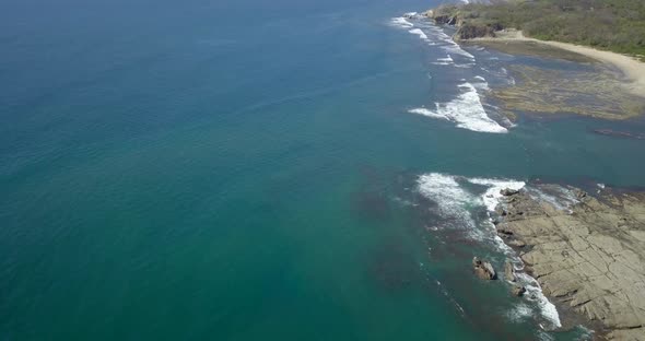 Aerial drone view of the beach, rocks and tide pools in Playa Palada, Guiones, Nosara, Costa Rica. alt