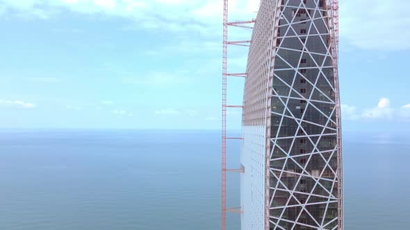 Aerial flight on a drone over construction site with tall tower crane building alt