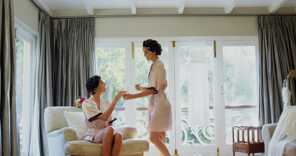 Excited bridesmaids in nightdress and hair rollers tossing a glass of champagne  alt
