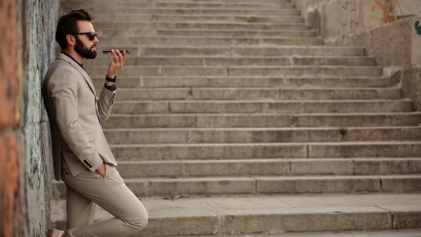 Serious Attractive Man Talking On Mobile Phone With Friend. Businessman Using Mobile Phone. alt