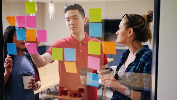 Mixed-race business people discussing over sticky notes in a modern office 4k alt