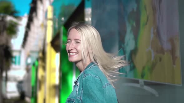 Rear view of young stylish blonde in denim jacket walking through city center alt