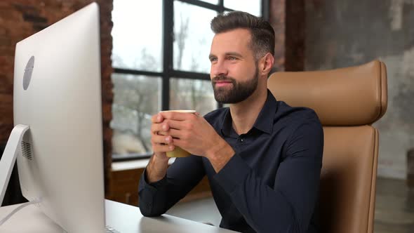 Cheerful Handsome Male Employee Drinking Morning Coffee on the Workplace
