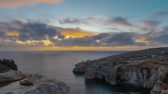 Blue Grotto, Malta. Breathtaking multicolored sunset with fluffy clouds drifting over the natural ar alt