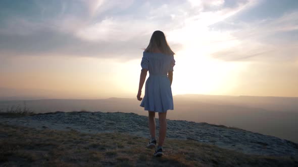 Girl in a beautiful summer dress in the mountains on the edge of the cliff of a large canyon