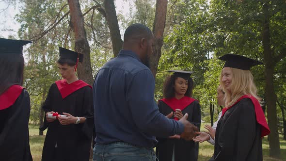 Happy Multiethnic Graduates and Academic Staff Talking After Graduation Ceremony alt