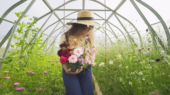 Happy Woman with Flowers Bouquet Walks Along Blooming Plants