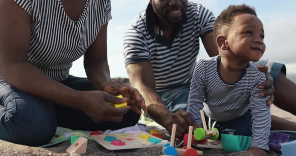 Happy african parents having fun on the beach with their son - Love concept alt