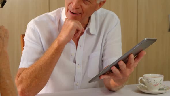 Senior man with digital tablet interacting to senior woman alt