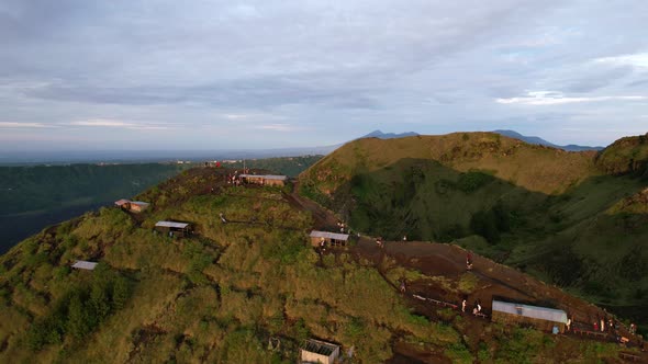 tourists in huts during sunrise golden hour at Mount Batur volcano in Bali Indonesia, aerial alt