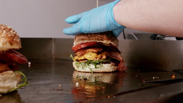 Tasty hamburger is being finished in restaurant kitchen. Ready to be served to costumer. alt