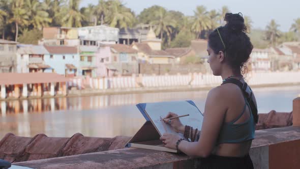 Side Portrait of Stylish Girl Drawing Picture Outdoors on Urban Tropical Background Sunny Day. Young alt